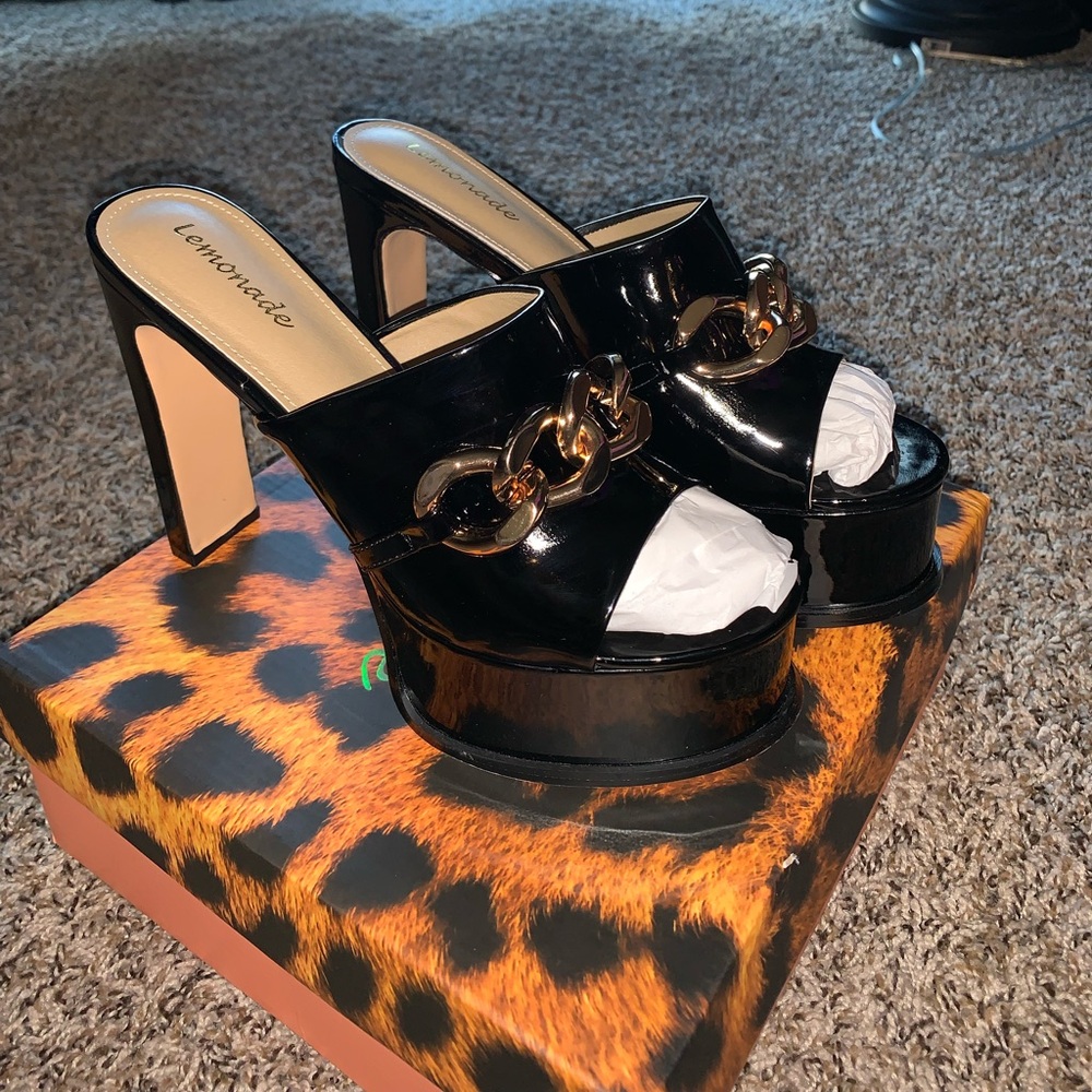 Fashionable black chunky heel with gold chain details and a shiny finish!
